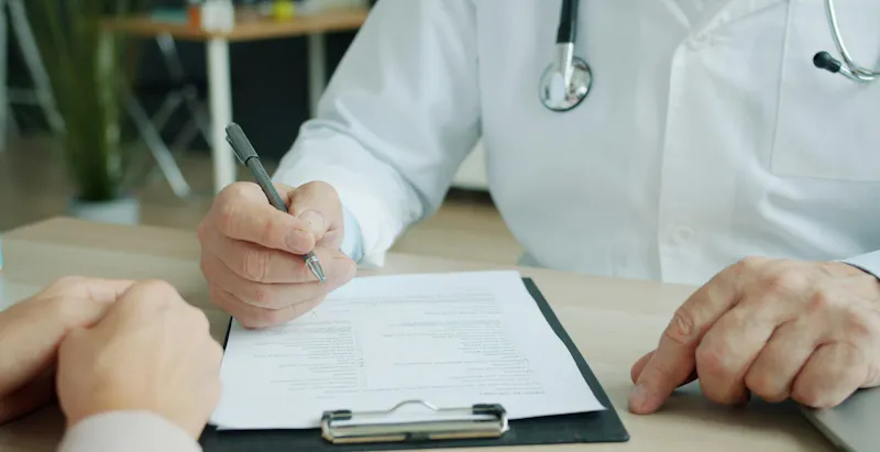 Doctor reviewing an appointment form with a patient at a desk